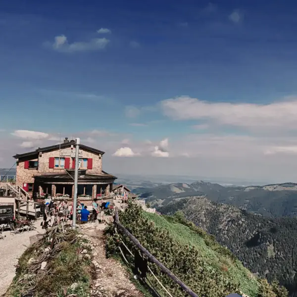 Ausblick auf eine Berghütte, blauer Himmel und Berge im Hintergrund