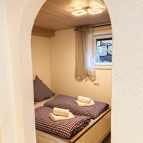 Schlafzimmer mit gemachtem Bett und kleinem Schrank im Sudterrain