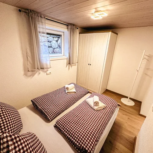 Schlafzimmer mit gemachtem Bett und kleinem Schrank im Sudterrain
