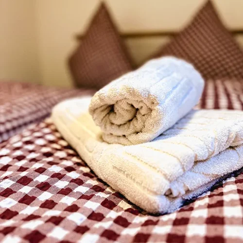 Handtücher gerollt und gefaltet auf einem Bett mit karierter Bettdecke