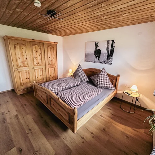 Ferienwohnung Rehgaiß Schlafzimmer mit Doppelbett und Schrank aus Holz Rehbild an der Wand