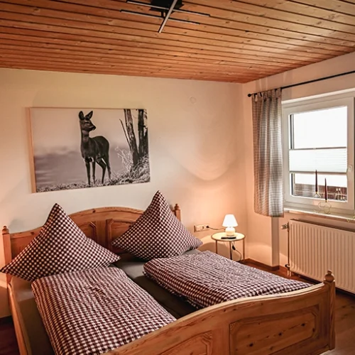 Schlafzimmer mit Holzmöbeln und Rehbild an der Wand